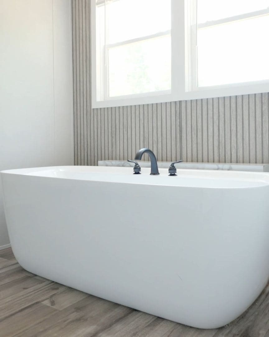 Freestanding porcelain soaking tub under a double window